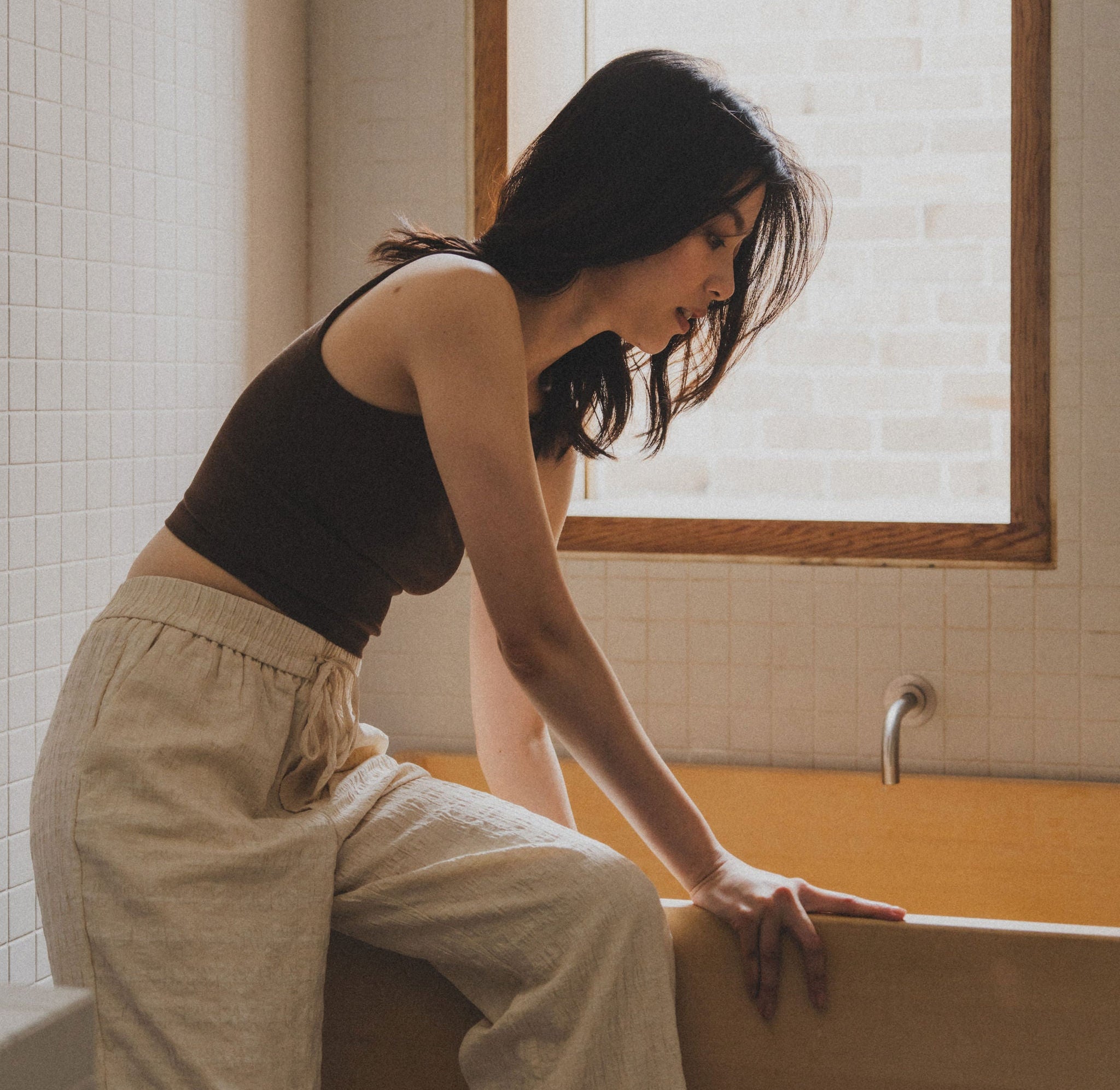 Woman sitting on the edge of a bathtub in a bathroom.